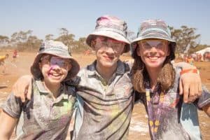 Three Scouts hugging covered in paint at a Scouting event  