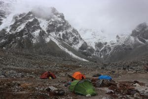 Snowy mountains with tents pitched in the forefront 
