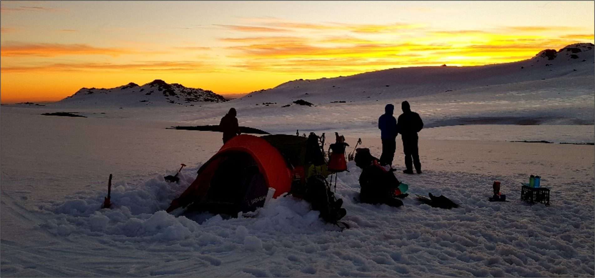 Scouts camping in the snow during sunset
